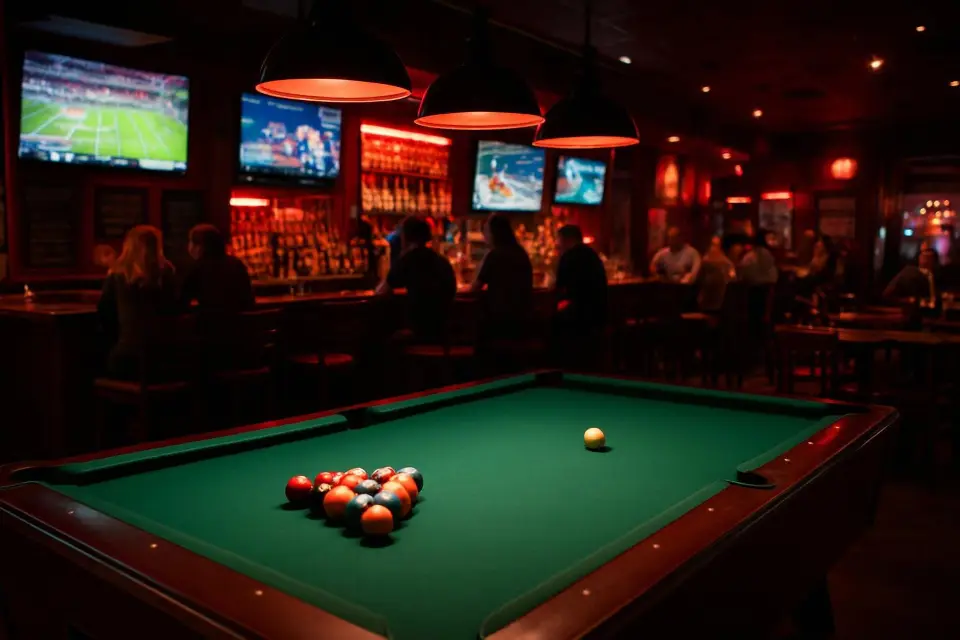 A pool table in a lively sports bar, with friends playing pool and watching the game on the big screens at Wizards Sports Cafe