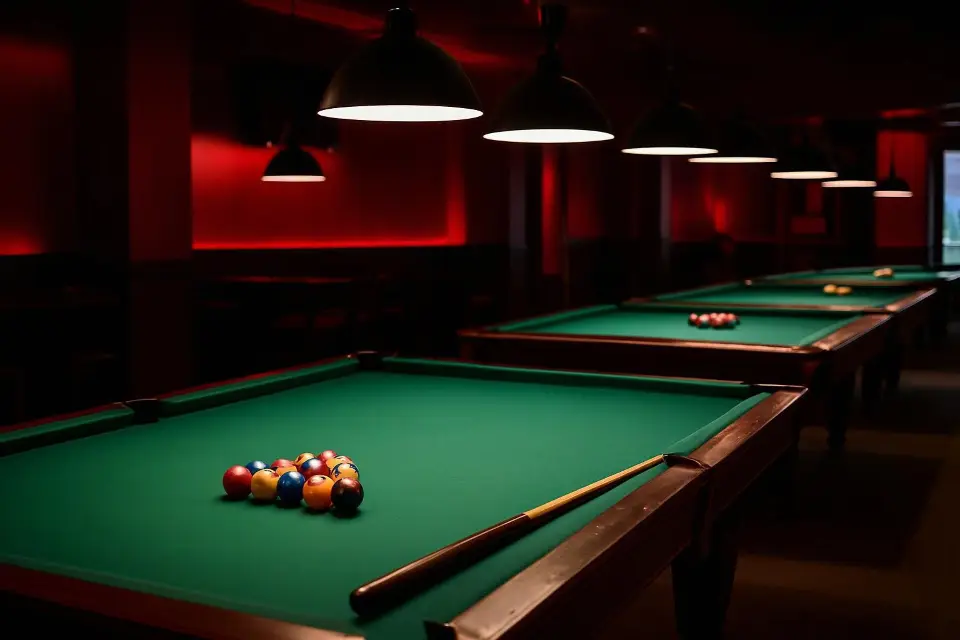 Row of pool tables with green felt and red-shaded lamps hanging overhead in the Wizards Sports Cafe pool hall